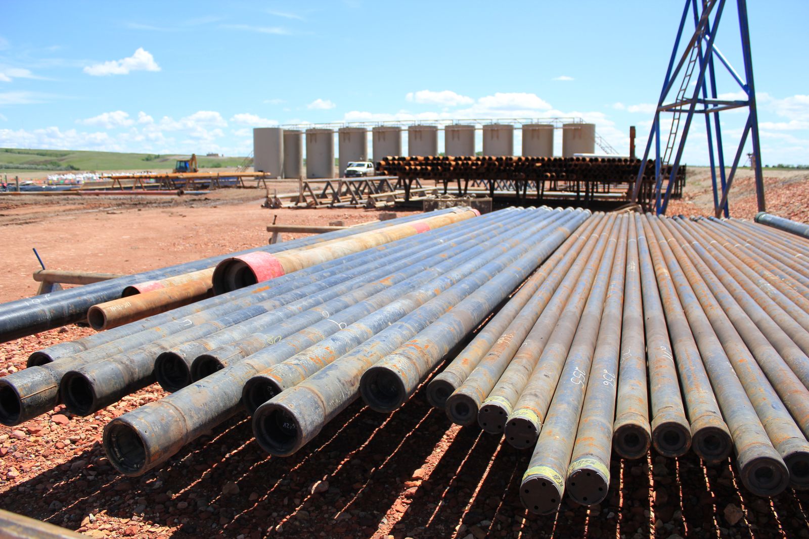 Rows of steel oilfield pipes racked by length at a drilling location